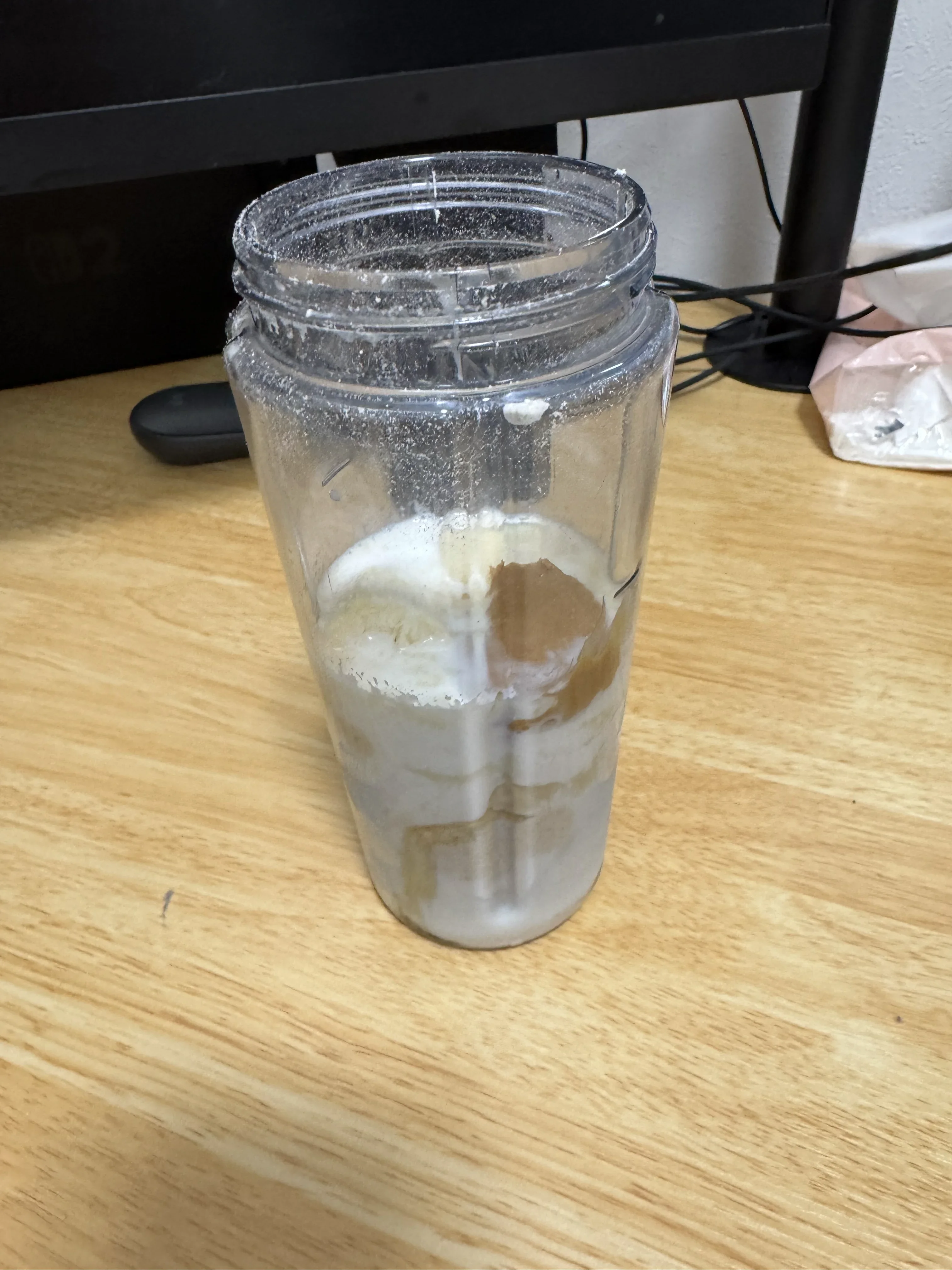 タンブラーに牛乳・プロテイン・ナッツなどの素材を入れたスムージーの材料