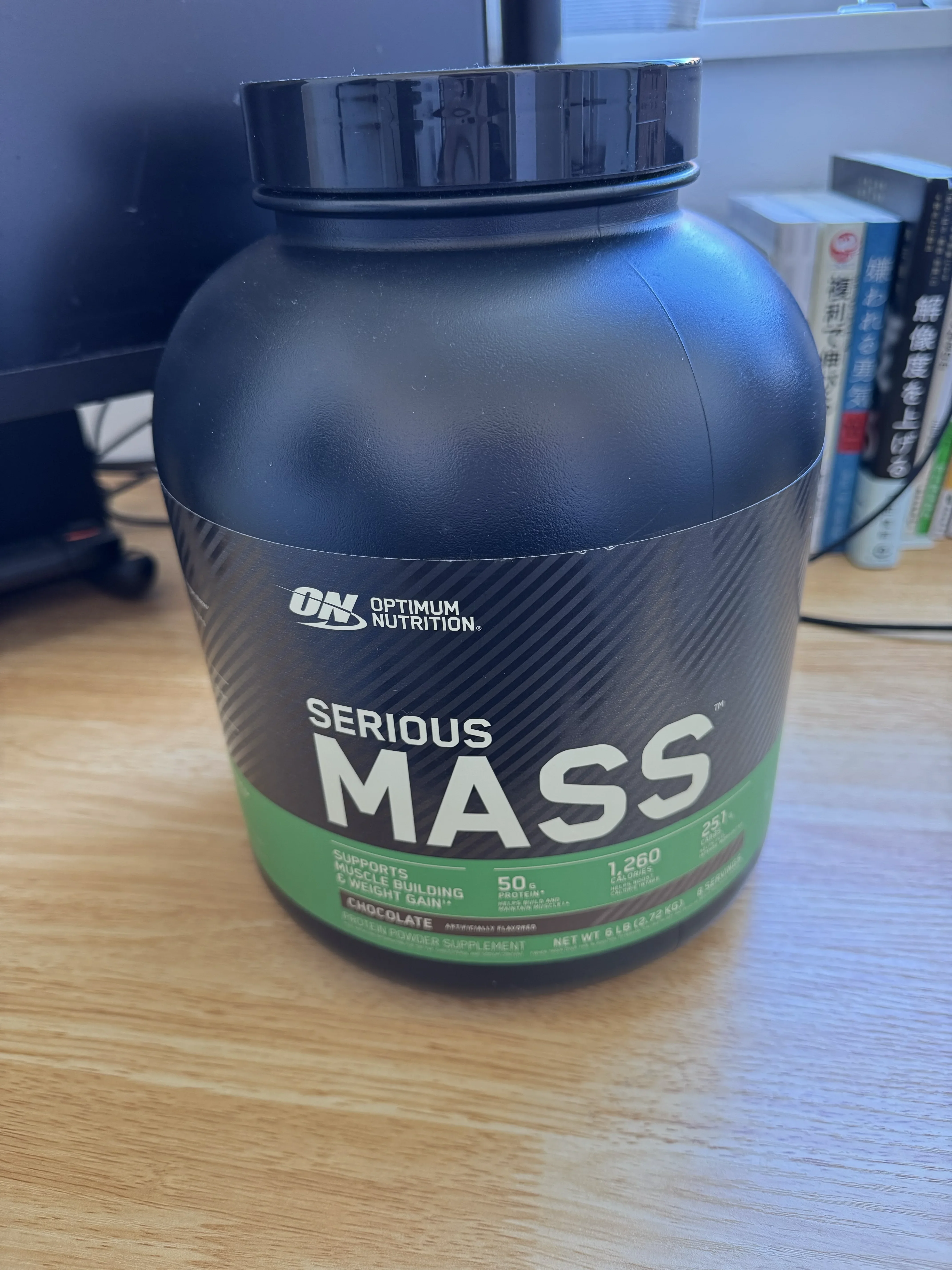 Optimum Nutrition Serious Mass チョコレート味の容器。デスクの上に置かれている。